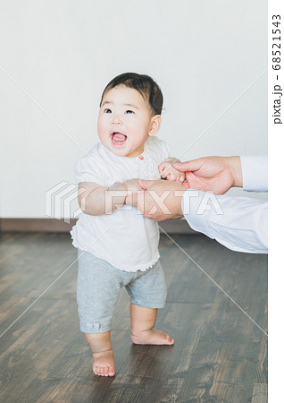 部屋でつかまり立ちする元気な赤ちゃんの写真素材