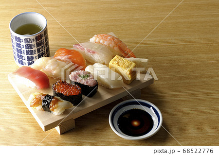 寿司下駄に盛られた鮪 帆立 サーモン いくら 海老 鯛 イカ 穴子 ネギトロ巻きの握り寿司とお茶の写真素材