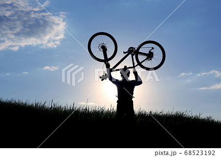 silhouette of a cyclist with a raised bike in the sun. silhouette of a cyclist with a raised bike in the sun. 68523192