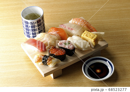 寿司下駄の上の鮪、帆立、サーモン、いくら、海老、鯛、イカ、穴子、ネギトロ巻きの握り寿司と熱いお茶 68523277