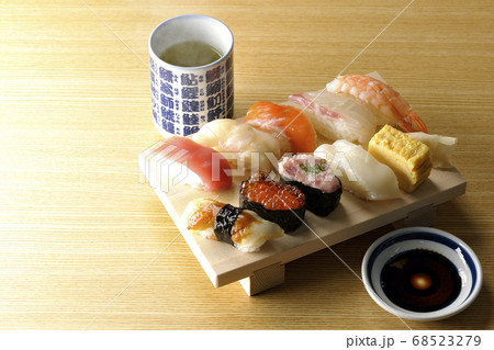 寿司下駄の上の鮪、帆立、サーモン、いくら、海老、鯛、イカ、穴子、ネギトロ巻きの握り寿司と熱いお茶 68523279