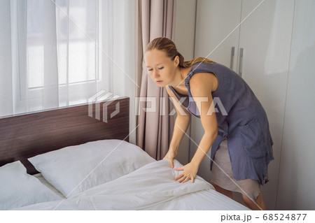 Young Female Housekeeper Changing Bedding In Hotel Room 68524877