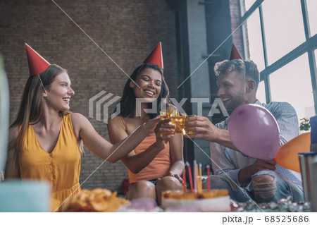 Three friends clinking glasses at the birthday party 68525686