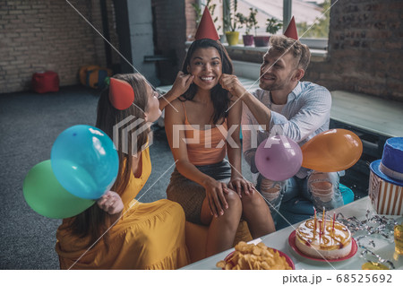 Friends touching womens cheeks during the birthday party Friends touching womens cheeks during the birthday party 68525692