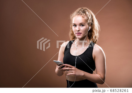 Young cheerful sportswoman in activewear and earphones scrolling in smartphone Young cheerful sportswoman in activewear and earphones scrolling in smartphone 68528261