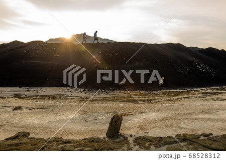 Tiny silhouettes of two contemporary researchers moving along hilltop 68528312