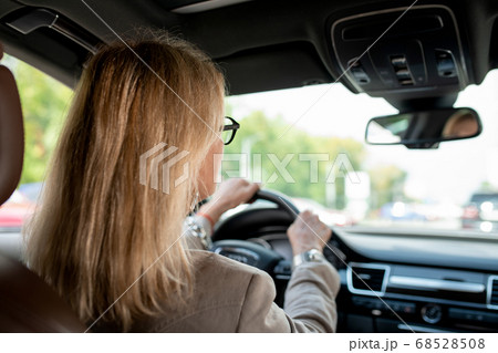 Woman with blond hair looking through front window while driving for meeting Woman with blond hair looking through front window while driving for meeting 68528508