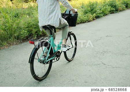 Rear view of young active female sitting on bicycle and moving down asphalt road 68528668