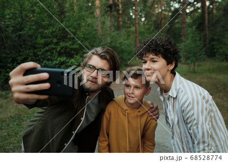 Contemporary family of happy parents and their son standing close to each other 68528774