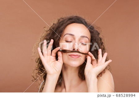 Gorgeous young female holding bunch of hair between lips and nose Gorgeous young female holding bunch of hair between lips and nose 68528994