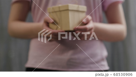 young woman stand and show brown gift box with twine bow 68530906