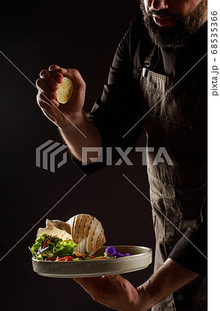 Chef watering lemon juice salad with vegetables and seafood. Chef watering lemon juice salad with vegetables and seafood. 68535366