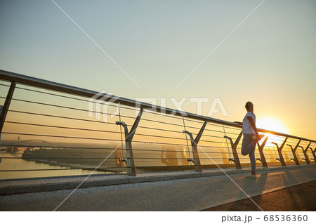 Sporty woman stretching legs on the bridge Sporty woman stretching legs on the bridge 68536360