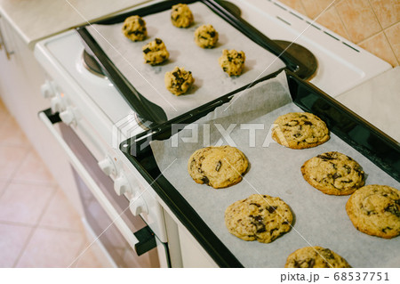 Two baking trays on the kitchen table - with cooked American cookies and raw dough balls. Two baking trays on the kitchen table - with cooked American cookies and raw dough balls. 68537751