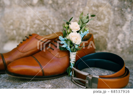 Stylish accessories for the groom, brown shoes, belt and bud on a mother-of-pearl background.  68537916