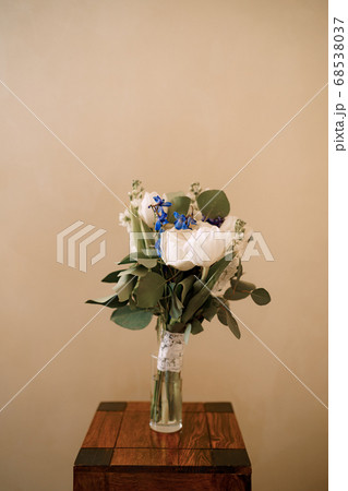 bridal bouquet of white tulips, delphinium, salal, limonium and lace ribbons in glass vase on the wooden stool 68538037