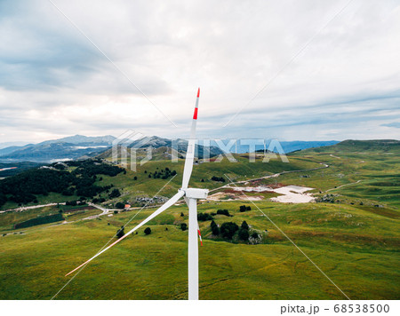 Aerial photo from the drone - a huge wind generator against the background of green meadows and hills in the mountains of Montenegro. Aerial photo from the drone - a huge wind generator against the background of green meadows and hills in the mountains of Montenegro. 68538500
