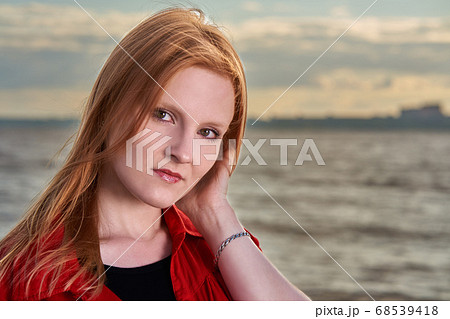 Portrait of a young red-haired girl in a red shirt Portrait of a young red-haired girl in a red shirt 68539418