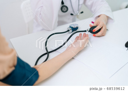 Close-up hands of unrecognizable female doctor measuring young pregnant woman patient pulse pressure 68539612