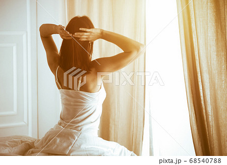 Woman stretching in bed after waking up, back view, entering a day happy and relaxed after good night sleep. Good morning and new day for brunette. Concept of Weekend, holidays Woman stretching in bed after waking up, back view, entering a day happy and relaxed after good night sleep. Good morning and new day for brunette. Concept of Weekend, holidays 68540788