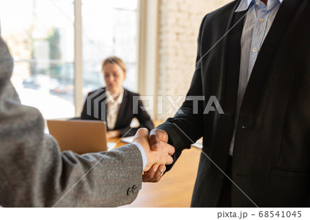 Close up of businessmen shaking hands in conference room Close up of businessmen shaking hands in conference room 68541045