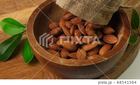 Hazelnuts are poured into a brown wooden bowl. 68541564