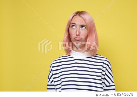 Annoyed young skeptical woman looking up isolated on yellow wall Annoyed young skeptical woman looking up isolated on yellow wall 68541679