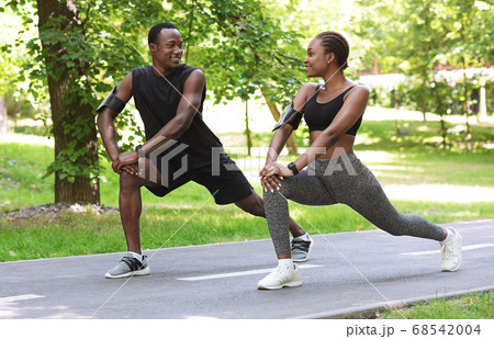 Sporty Black Couple Preparing For Marathon Together, Stretching Muscles Before Jogging Outdoors 68542004