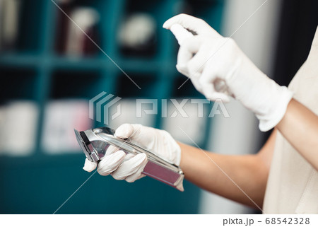 Master disinfecting trimmer after work, close up 68542328