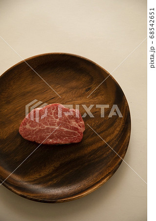 アカシアプレートにのせた生の肉厚牛フィレステーキ 68542651