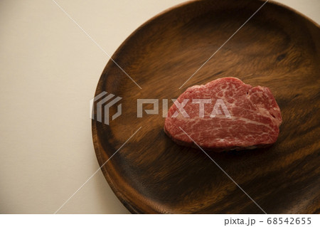 アカシアプレートにのせた生の肉厚牛フィレステーキ 68542655