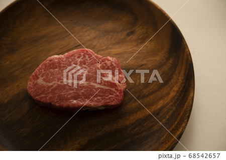 アカシアプレートにのせた生の肉厚牛フィレステーキ 68542657