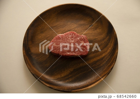 アカシアプレートにのせた生の肉厚牛フィレステーキ 68542660