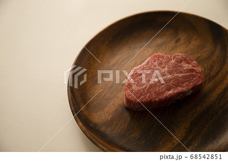 アカシアプレートにのせた生の肉厚牛フィレステーキ 68542851