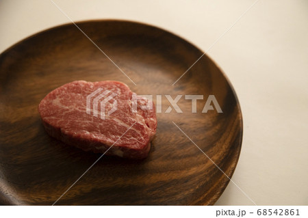 アカシアプレートにのせた生の肉厚牛フィレステーキ 68542861