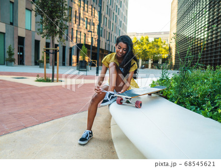 pretty athletic girl sitting with a longboard in modern city 68545621