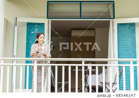 Beautiful asian woman having morning coffee or tea at hotel balcony. Beautiful asian woman having morning coffee or tea at hotel balcony. 68546147