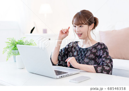 リビングでズームで友達と話をしながらお茶を飲む若い女性 68546358