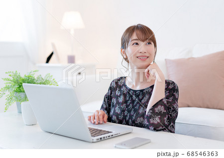 リビングでズームで友達と話をしながらお茶を飲む若い女性 リビングでズームで友達と話をしながらお茶を飲む若い女性 68546363