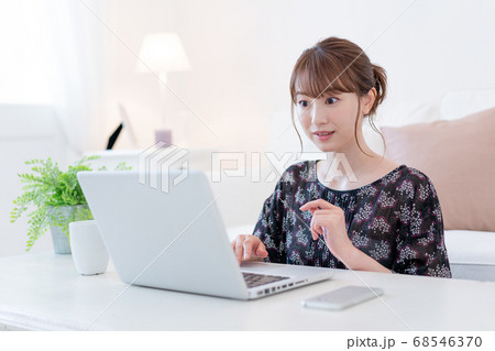 リビングでズームで友達と話をしながらお茶を飲む若い女性 リビングでズームで友達と話をしながらお茶を飲む若い女性 68546370