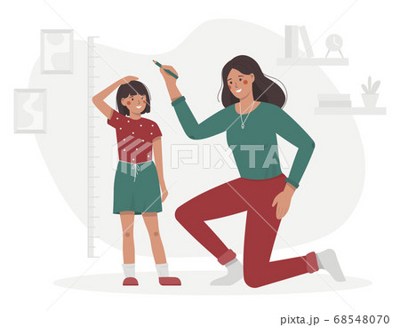 Mother measures the child height in the room 68548070