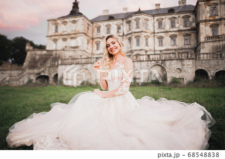 Beautiful bride in elegant white dress holding bouquet posing in park 68548838