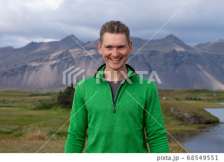 Backside of tall caucasian man wearing green jacket standing in over mountain and fog background. Promoting healthy lifestyle Backside of tall caucasian man wearing green jacket standing in over mountain and fog background. Promoting healthy lifestyle 68549551