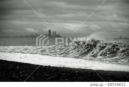 Splashing storm with big waves hitting the sea coast in the evening. Black and white photo 68549652