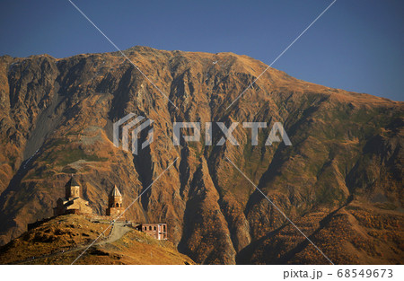 Beautiful view of Gergeti Trinity Church under Mount Kazbegi. Background of autumn mountains and sky, Caucasus, Georgia Beautiful view of Gergeti Trinity Church under Mount Kazbegi. Background of autumn mountains and sky, Caucasus, Georgia 68549673