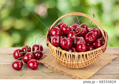 red sweet cherry in a wicker basket on wooden table isolated on white background with clipping path and full depth of field 68550829