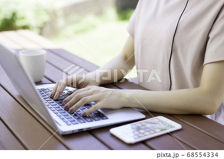 庭でテレワークをする若い女性の手元 68554334