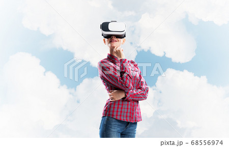 Girl in checked shirt wearing VR glasses experiencing another reality 68556974