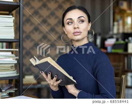 Portrait of young woman with book in a library Portrait of young woman with book in a library 68558441