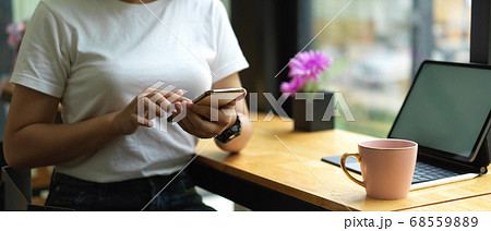 Female using smartphone while sitting at worktable 68559889